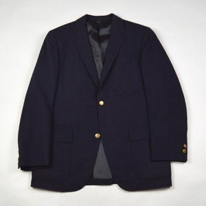 May include: A navy blue blazer with gold-colored buttons. The blazer has two front pockets and a chest pocket. The interior lining is black. The blazer is made of a wool-like material.