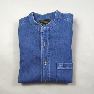 May include: A folded blue denim shirt with a mandarin collar and a single chest pocket. The shirt has gold-colored buttons and the brand name "Croft & Barrow" is visible on the label.