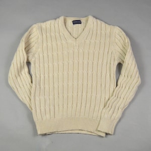 May include: Cream-coloured V-neck jumper with a textured, vertical cable knit pattern. The long-sleeved jumper has ribbed cuffs and hem. A small label is visible at the back of the neck.