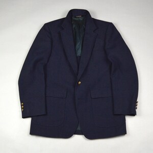 Puede incluir: Un blazer azul marino con botones dorados. El blazer tiene dos bolsillos delanteros y una solapa con muescas. El forro interior es de color verde oscuro.