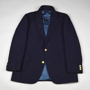 May include: A navy blue blazer with gold buttons. The blazer has a classic design with a notched lapel and two front pockets. The interior lining is a bright blue color.