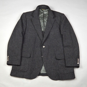 May include: A charcoal gray blazer with a two-button closure and notched lapels. The jacket has two front pockets and three buttons on each cuff. The interior lining is a light green color.