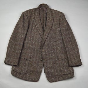 May include: A brown tweed blazer with a two-button closure, two front pockets, and a notched lapel. The jacket has a subtle flecked pattern and a classic, tailored fit. The blazer is a versatile piece for a smart casual wardrobe.
