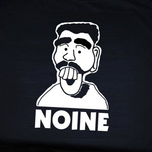 May include: Black t-shirt with a white cartoon graphic of a man with a mustache and large teeth. The word "NOINE" is printed below the graphic. The sleeve has the text "HELLO HELLO".
