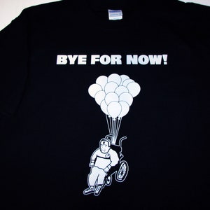 May include: Black t-shirt with white text that says "BYE FOR NOW!" and a graphic of a person in a wheelchair being lifted by balloons.