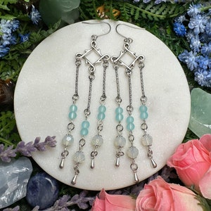 May include: A pair of silver dangle earrings with a geometric design and blue and white beads.