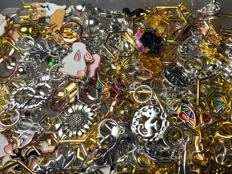 May include: A large collection of silver and gold charms, including a rabbit, a sunflower, a bee, a pineapple, a leaf, a hexagon, and a starfish. The charms are all different sizes and shapes and are perfect for adding to a bracelet or necklace.