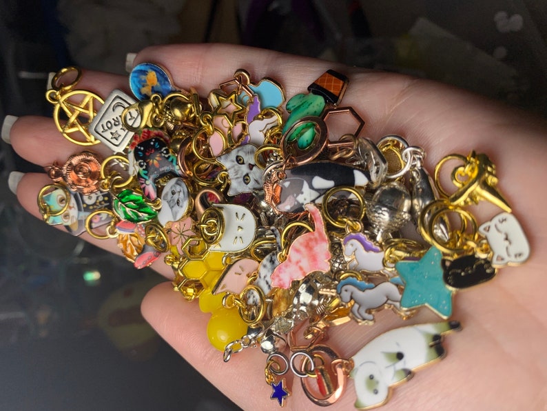 A completely random assortment of colorful  metal, enamel, and acrylic stitch markers in a hand
