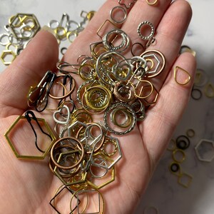 May include: A variety of gold, silver, and copper-toned metal rings, circles, and geometric shapes. The shapes include hexagons, stars, and squares.