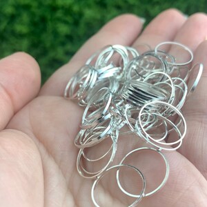 Puede incluir: Un mont&oacute;n de anillos de salto de plata, un tipo de hallazgo de joyer&iacute;a, en una mano. Los anillos son de varios tama&ntilde;os y son perfectos para la elaboraci&oacute;n.