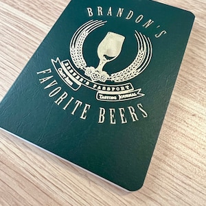May include: A green passport-style notebook with a gold design featuring a beer glass, wheat stalks, and the text "Brandon's Favourite Beers Brewer's Passport Tasting Journal".