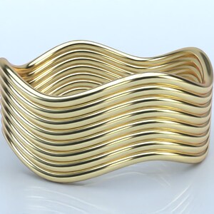 May include: A gold-colored, wavy cuff bracelet. The bracelet features a series of parallel, undulating bands that create a fluid, textured appearance. The design is sleek and modern, with a polished finish.
