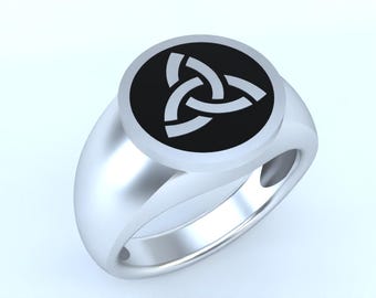 May include: A silver ring with a black circular inlay featuring a white Celtic knot design.