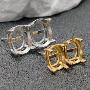 May include: Two pairs of earring settings, one silver-toned and one gold-toned, are displayed. Each setting features a rectangular design with a central post for securing the earring. The settings are designed to hold gemstones or other decorative elements.