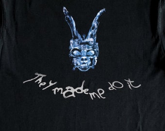 May include: Black t-shirt with a blue and white graphic of a rabbit mask with the text "They made me do it" printed in silver.