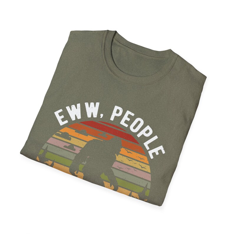 May include: A green t-shirt with a vintage-style graphic of a Bigfoot silhouette standing in front of a sunset with the text "EWW, PEOPLE".