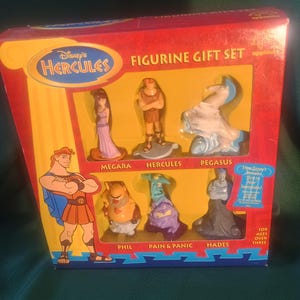 May include: A Disney's Hercules figurine gift set in a red and yellow box. The set includes figurines of Megara, Hercules, Pegasus, Phil, Pain & Panic, and Hades. The box has the Disney's Hercules logo and the word "applause".