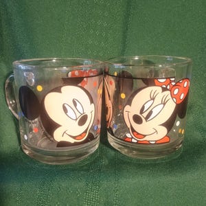 Pu&ograve; includere: Due tazze di vetro trasparente con Topolino e Minnie. Topolino &egrave; su una tazza e Minnie sull'altra. Entrambe le tazze hanno immagini di cartoni animati in bianco e nero con coriandoli colorati. Le tazze hanno manici e sono di The Walt Disney Company.
