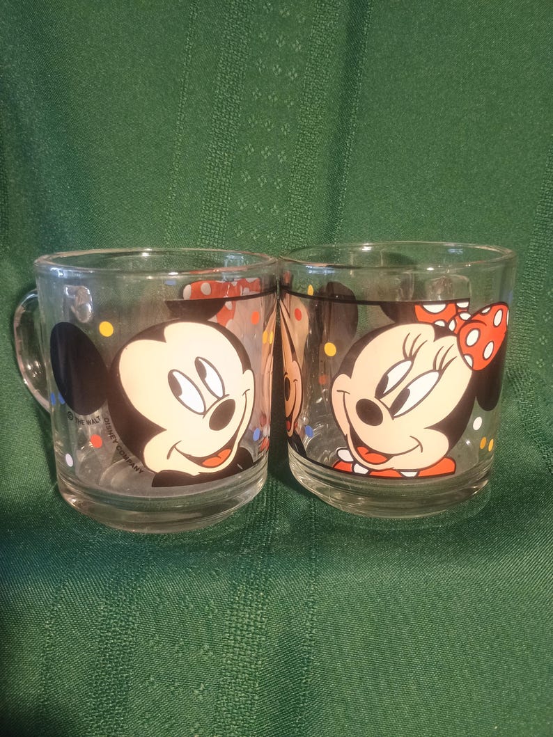 Pu&ograve; includere: Due tazze di vetro trasparente con Topolino e Minnie. Topolino &egrave; su una tazza e Minnie sull'altra. Entrambe le tazze hanno immagini di cartoni animati in bianco e nero con coriandoli colorati. Le tazze hanno manici e sono di The Walt Disney Company.