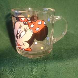 Pu&ograve; includere: Tazza di vetro trasparente con Minnie Mouse. La tazza ha un manico ed &egrave; decorata con un'immagine colorata di Minnie Mouse, incluso il suo fiocco distintivo a pois bianchi. La tazza ha anche pois colorati intorno al vetro.