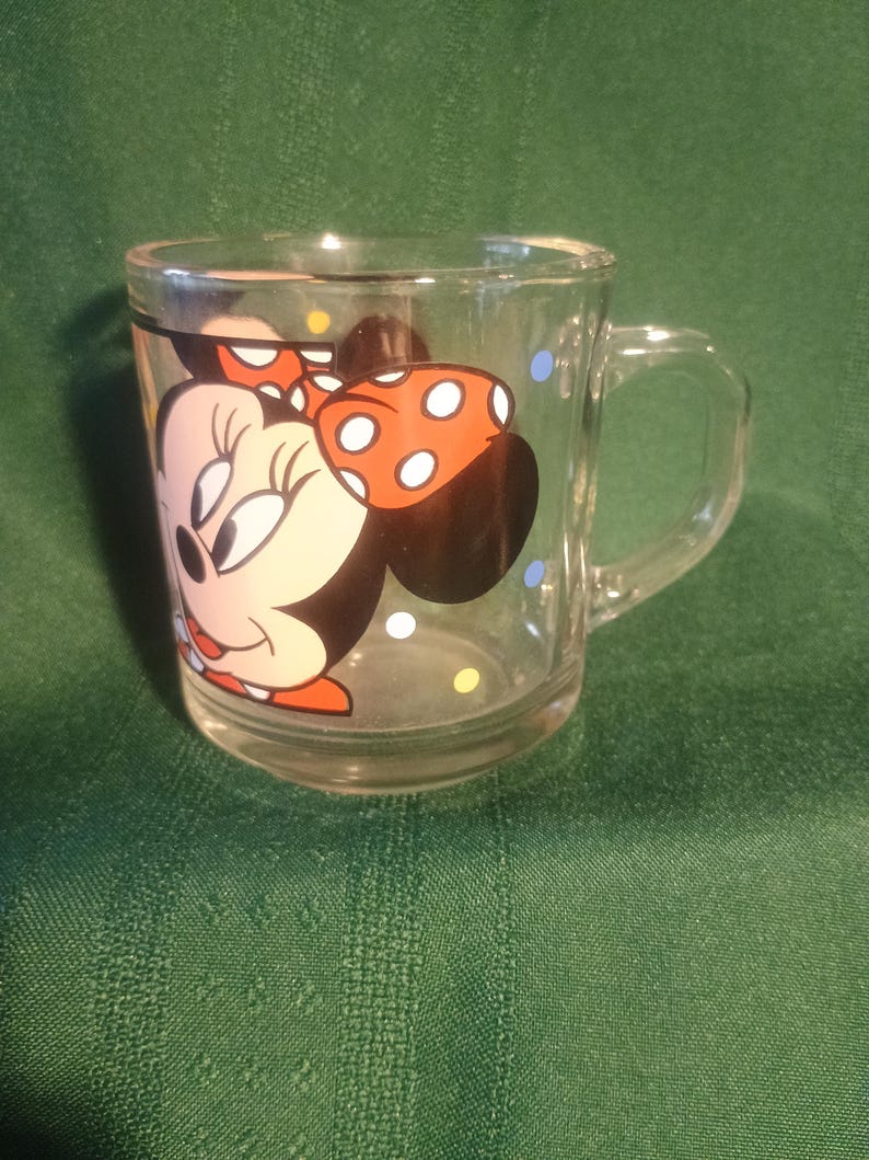 Pu&ograve; includere: Tazza di vetro trasparente con Minnie Mouse. La tazza ha un manico ed &egrave; decorata con un'immagine colorata di Minnie Mouse, incluso il suo fiocco distintivo a pois bianchi. La tazza ha anche pois colorati intorno al vetro.