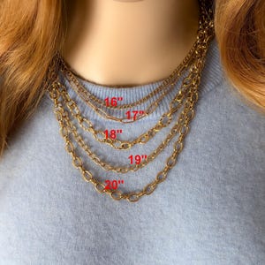 Op de afbeelding: Een set van vijf gelaagde goudkleurige metalen kettingen met verschillende stijlen en schakelgroottes. Rode tekst geeft de lengtes van 16, 17, 18, 19 en 20 inch aan voor elk van de respectievelijke kettingen.