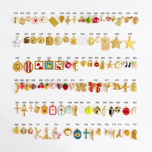May include: A collection of small metal charms arranged in rows, each labeled with a number from 618 to 713. The charms feature various shapes including hearts, stars, fruits, sports equipment, and symbols, finished in gold-tone metal and enamel.