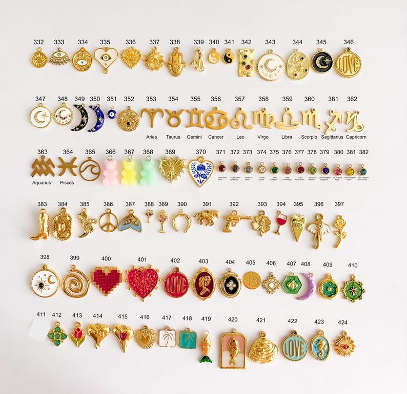 May include: A collection of gold-toned metal charms arranged in rows, numbered 332 through 424. The charms feature various shapes including celestial symbols, zodiac signs, hearts, flowers, animals, and colorful enamel accents on a white background.