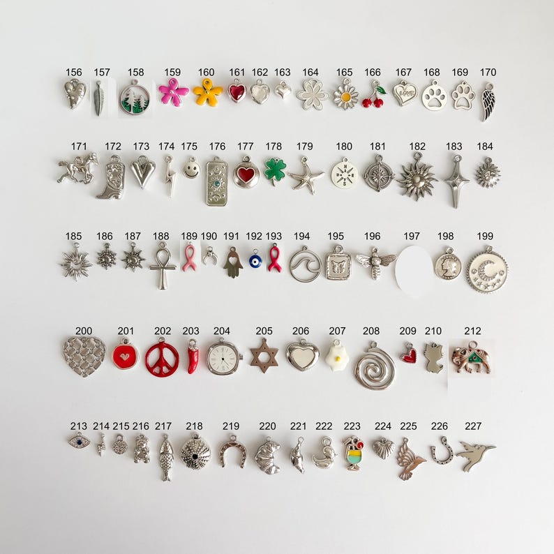 May include: A collection of metal charms arranged in rows and numbered from 156 to 227. The charms feature various shapes including hearts, flowers, animals, symbols, and food items, with some incorporating colored enamel accents.