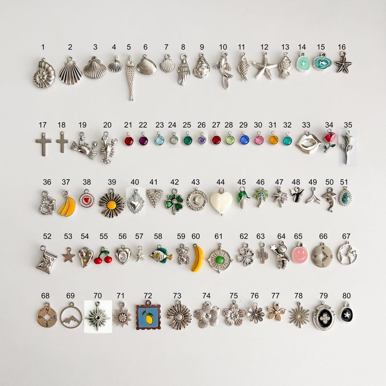 May include: A collection of eighty silver-toned metal charms arranged in rows and numbered one through eighty. The charms feature various shapes including sea life, flowers, fruits, geometric symbols, and colorful gemstone accents.