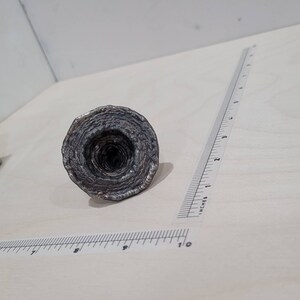 Peut inclure: Une sculpture en m&eacute;tal argent&eacute; en forme de spirale, ressemblant &agrave; un entonnoir ou un vortex. La sculpture est faite de m&eacute;tal mince et superpos&eacute;, cr&eacute;ant un design textur&eacute; et complexe.