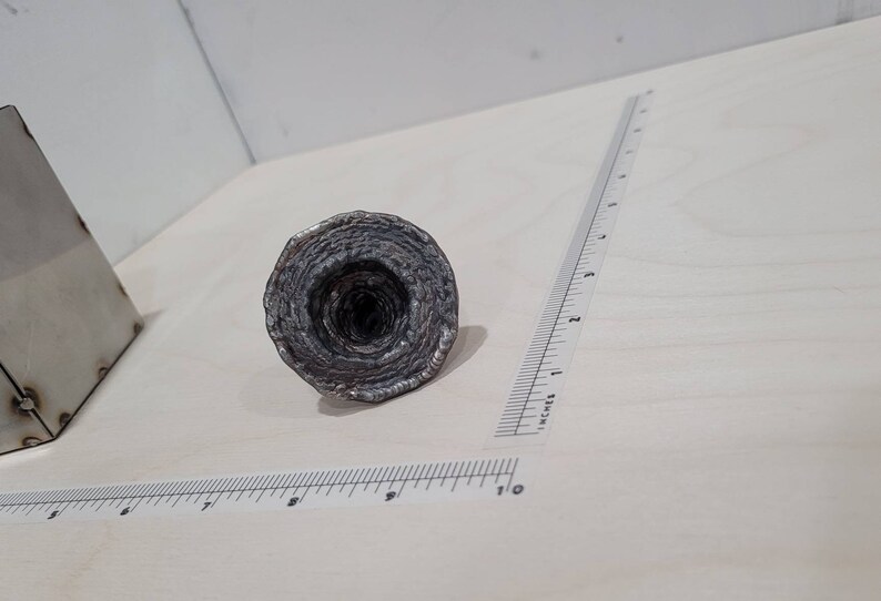 Peut inclure: Une sculpture en m&eacute;tal argent&eacute; en forme de spirale, ressemblant &agrave; un entonnoir ou un vortex. La sculpture est faite de m&eacute;tal mince et superpos&eacute;, cr&eacute;ant un design textur&eacute; et complexe.