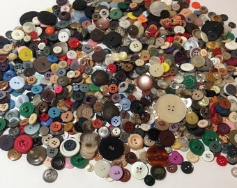 May include: A large collection of assorted buttons in various colors, sizes, and materials. The buttons are a mix of plastic, metal, and fabric.