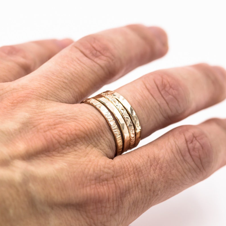 minimalist boho 14K yellow gold fill hammered ring band worn on finger with other pattern rings for a ring stack