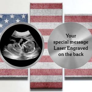 May include: A multi-panel artwork featuring the American flag design. A sonogram image is centered, surrounded by a silver frame. A silver disc with the text "Your special message Laser Engraved on the back" is also present.