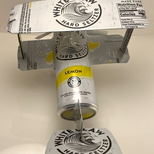 K&ouml;nnte beinhalten: Eine White Claw Hard Seltzer Dose mit Zitronengeschmack, die in ein Modellflugzeug verwandelt wurde. Die Dose ist gelb mit schwarzem Text und einem Wellendesign. Die Fl&uuml;gel und der Schwanz sind aus dem oberen und unteren Teil der Dose gefertigt.