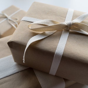 May include: Three brown paper gift boxes tied with white ribbon. The top box has a large bow.