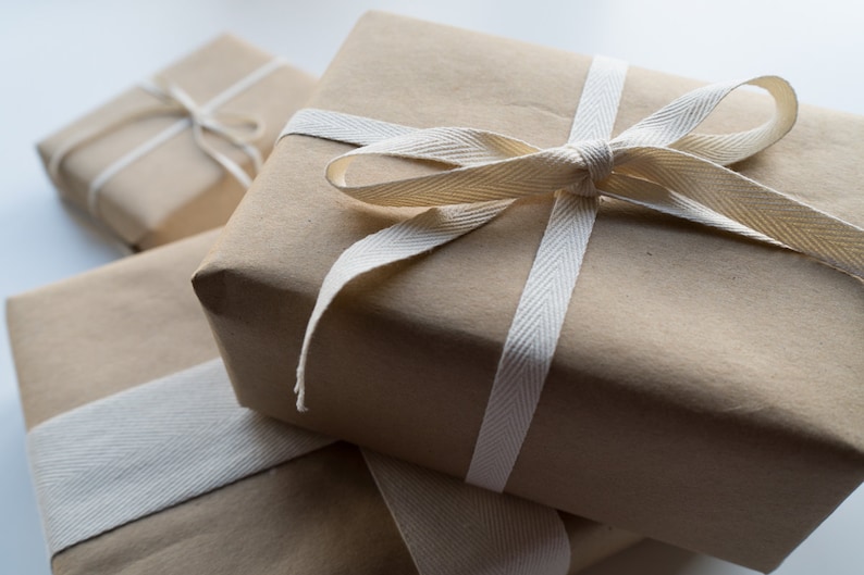 May include: Three brown paper gift boxes tied with white ribbon. The top box has a large bow.