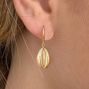 Può includere: Orecchini dorati con un design a conchiglia. Gli orecchini sono di stile semplice e delicato.