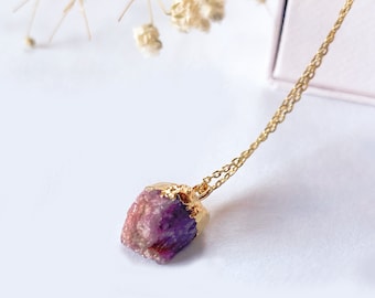 May include: A gold chain necklace with a raw purple and pink crystal pendant.