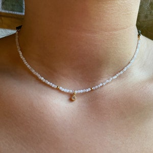 A dainty moonstone choker, really tiny with a small white cz charm in a woman neck, it looks really delicate