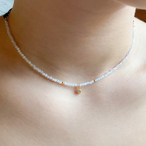 A dainty moonstone choker, really tiny with a small white cz charm in a woman neck, it looks really delicate