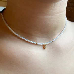 A dainty moonstone choker, really tiny with a small white cz charm in a woman neck, it looks really delicate