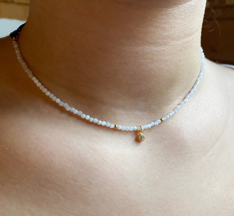 A dainty moonstone choker, really tiny with a small white cz charm in a woman neck, it looks really delicate