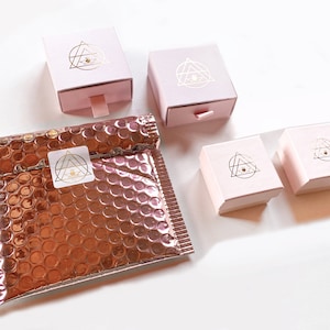 Pink packaging in different sizes with gold logo in a white background