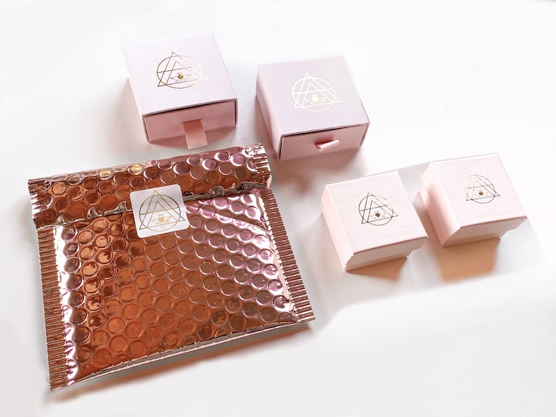 Pink packaging in different sizes with gold logo in a white background
