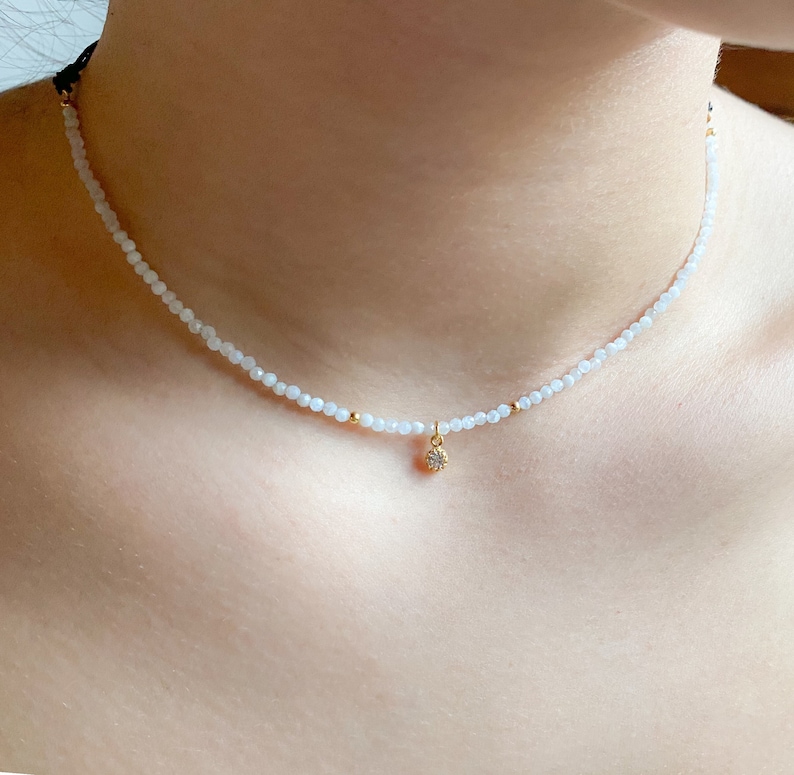 A dainty moonstone choker, really tiny with a small white cz charm in a woman neck, it looks really delicate