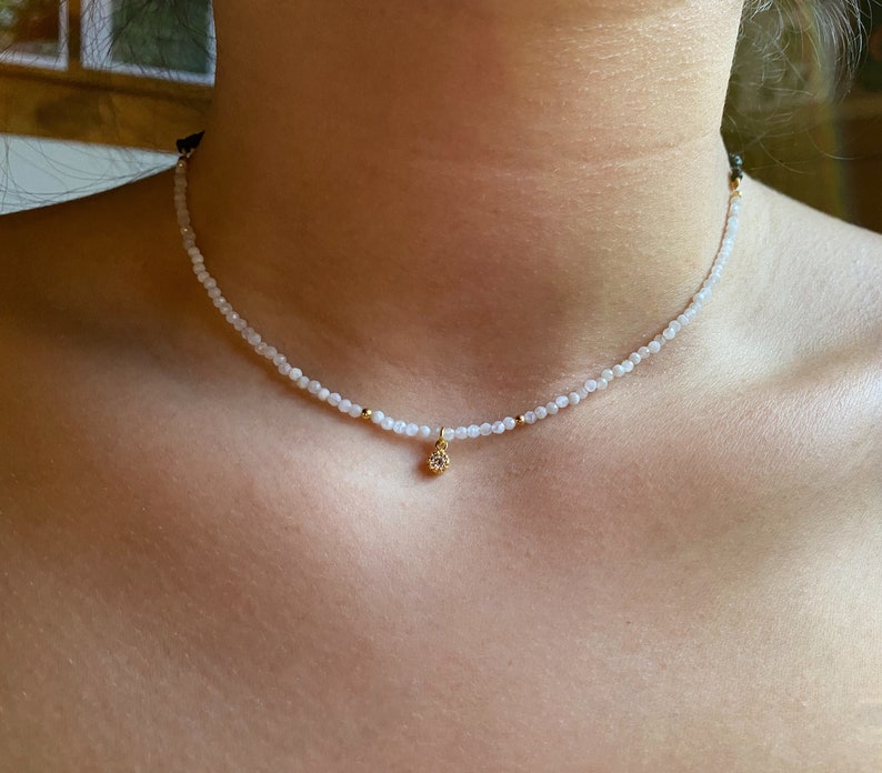 A dainty moonstone choker, really tiny with a small white cz charm in a woman neck, it looks really delicate