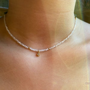 A dainty moonstone choker, really tiny with a small white cz charm in a woman neck, it looks really delicate