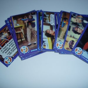 May include: A collection of vintage trading cards featuring characters from the television show "The Facts of Life". The cards are purple and blue with a globe design and feature text such as "If this is soap opera, Mindy where are the singing detergent?" and "My favorite dessert".